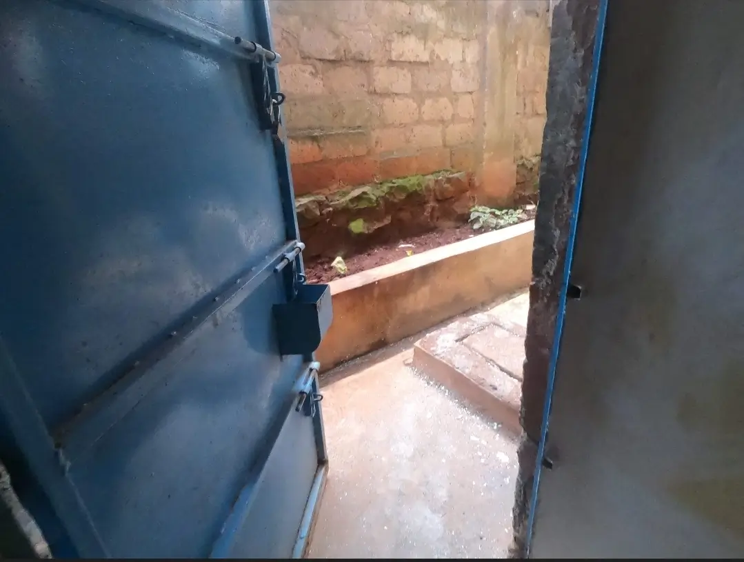 Open blue gate revealing compound entrance and paved area