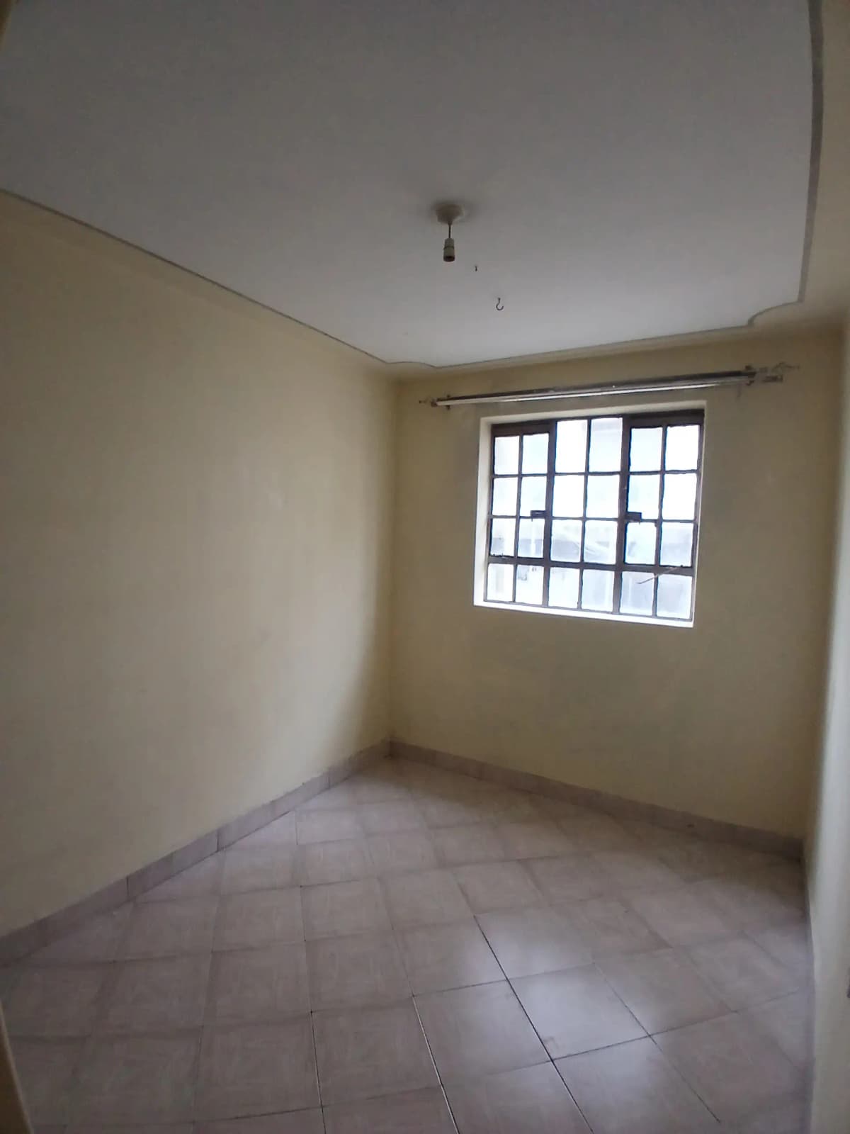 Empty bedroom with barred window and tiled flooring