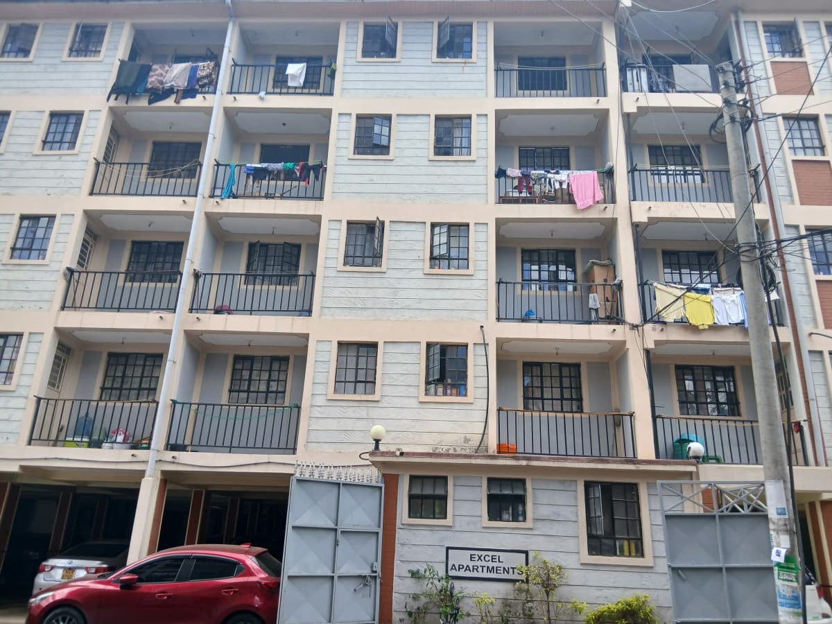 Multi-story residential building facade with balconies and ground-floor parking