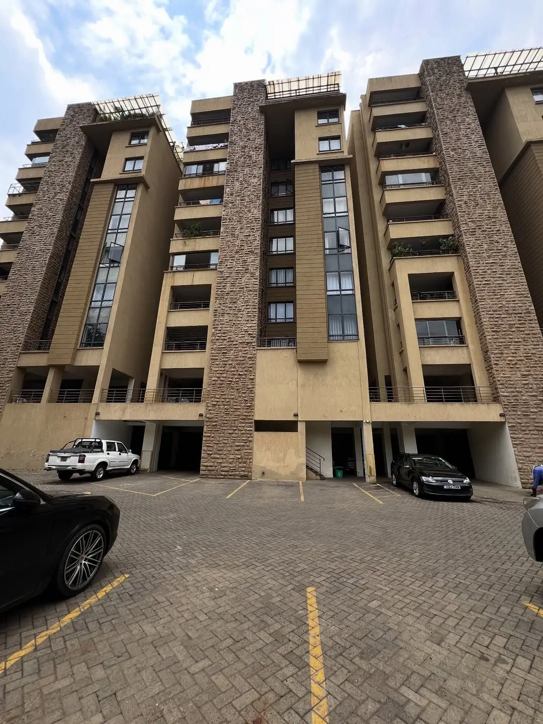 Modern multi-story residential building with brick accents and parking bays
