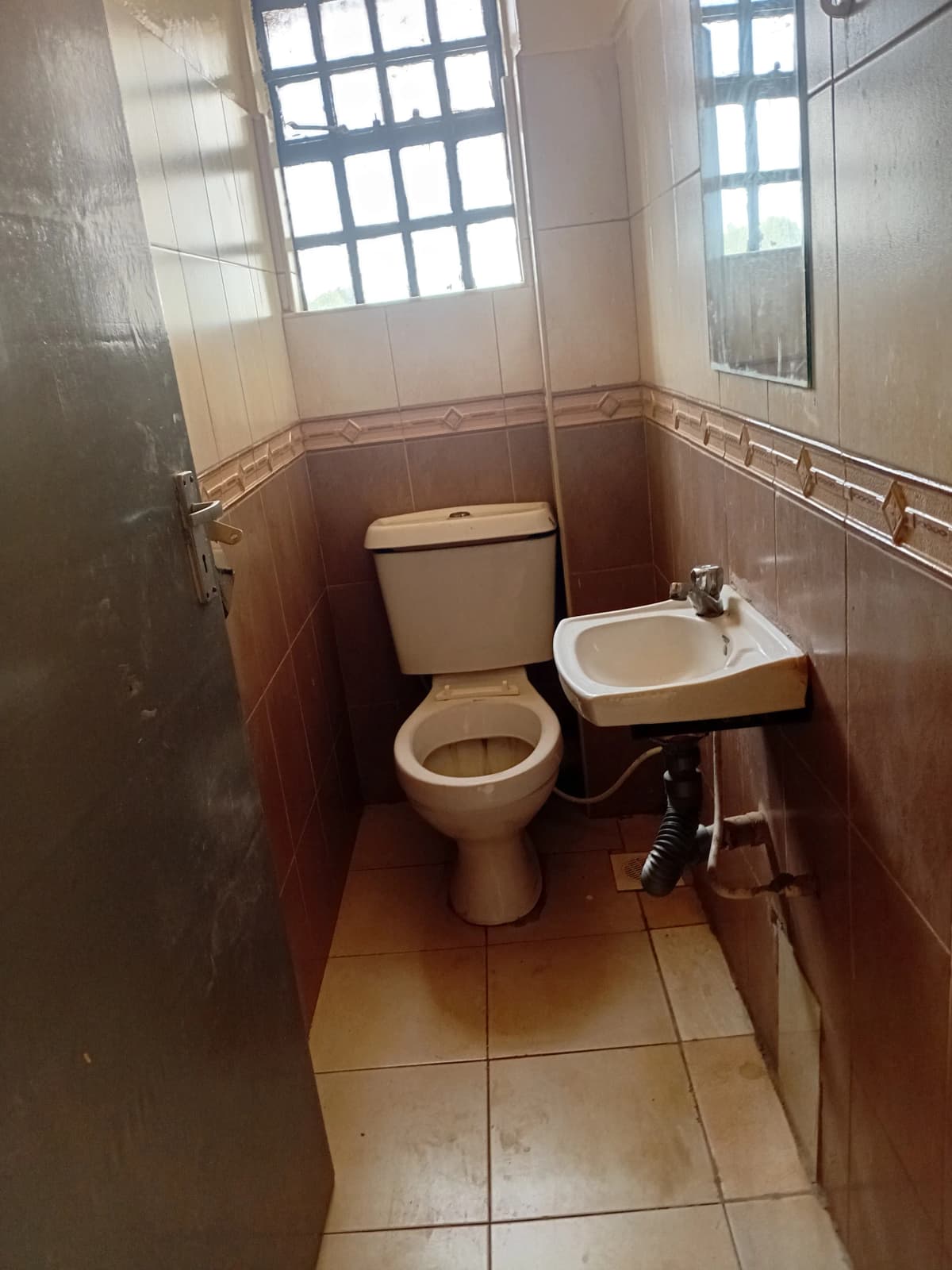 Small bathroom with toilet, sink, and tiled walls