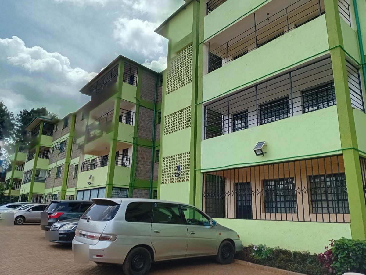 Multi-story residential building with green facade and parking area