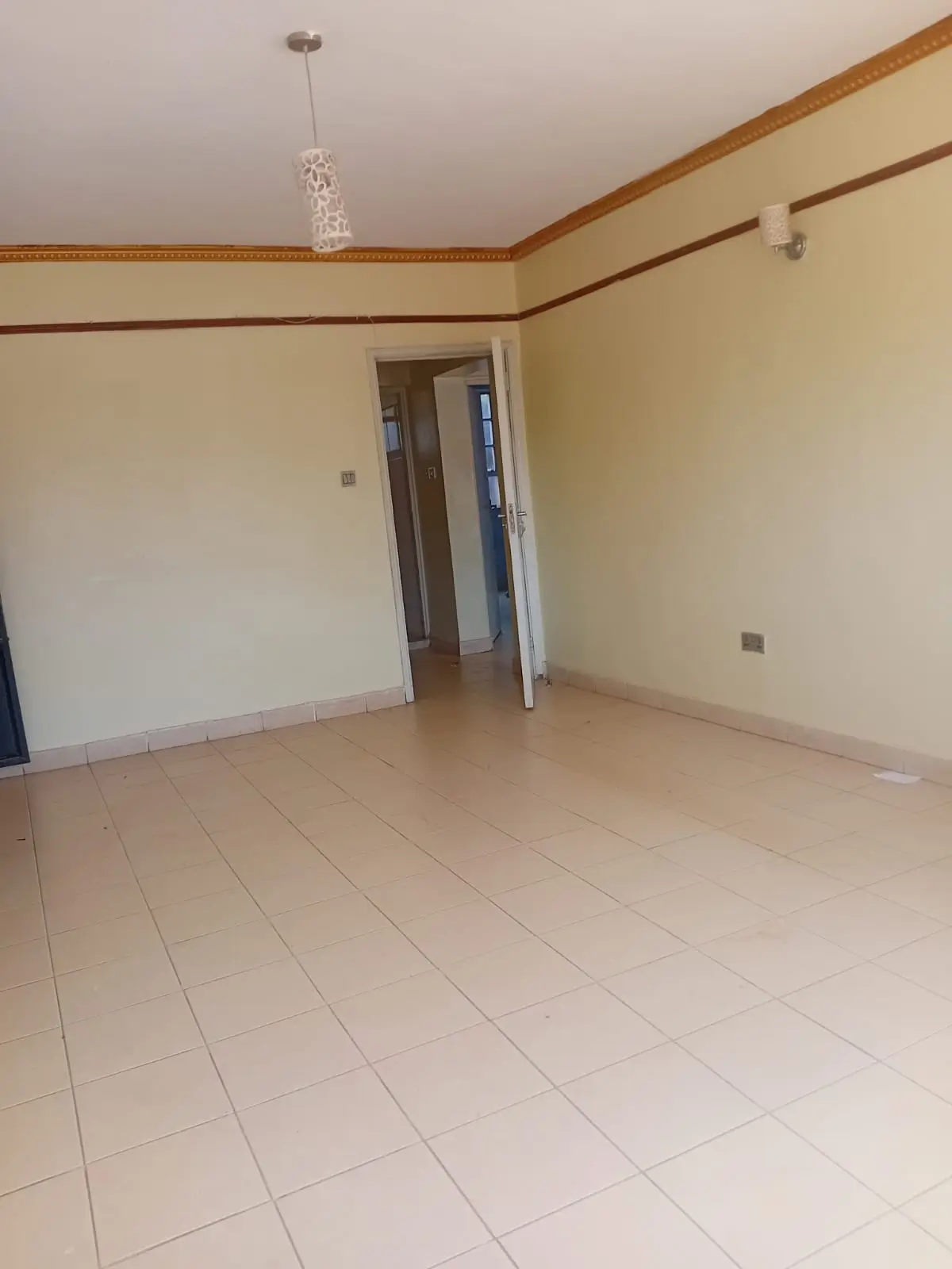 Spacious empty living room with tiled flooring and wooden trim