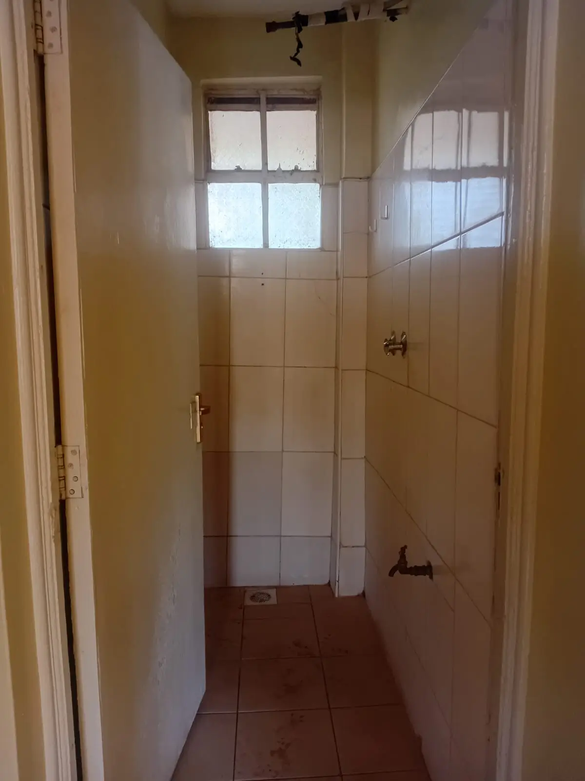 Narrow bathroom with tiled walls and small window