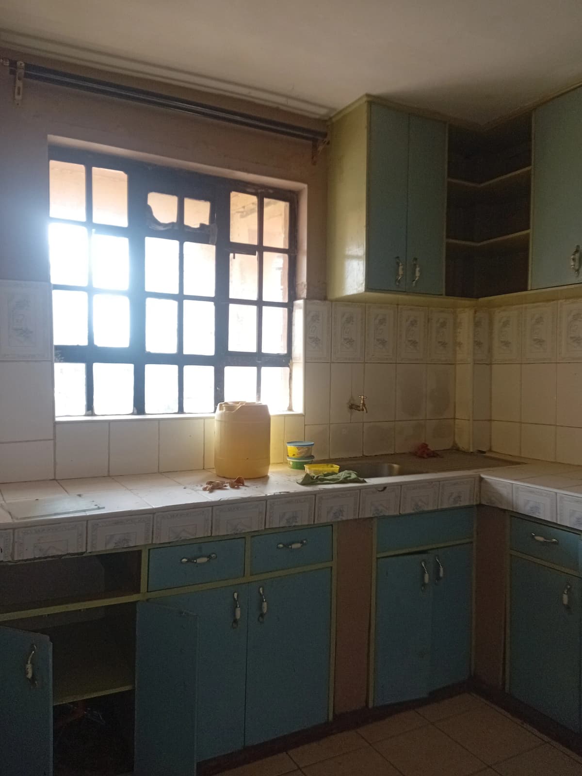 Compact kitchen with teal cabinets and tile countertops