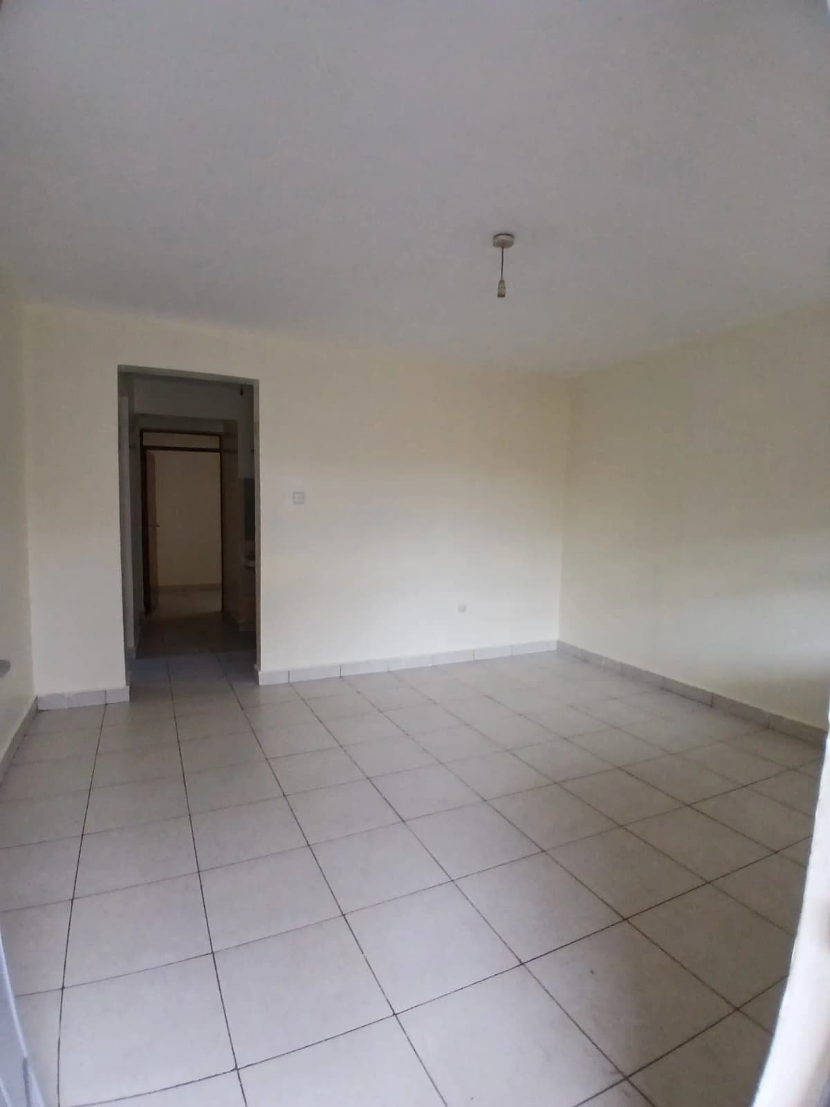 Empty living room with tiled flooring and entrance door