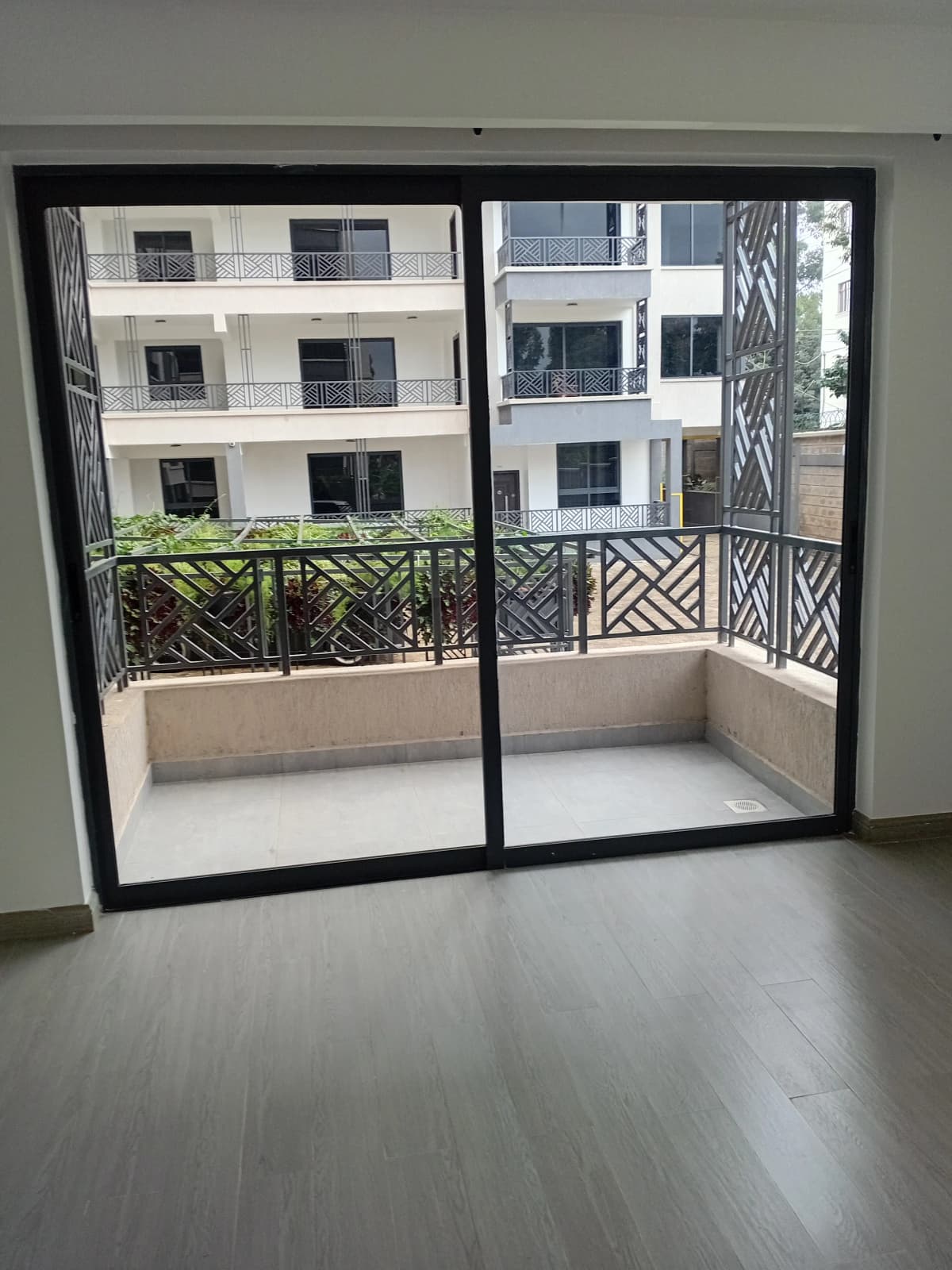 Spacious balcony with geometric railing overlooking residential buildings