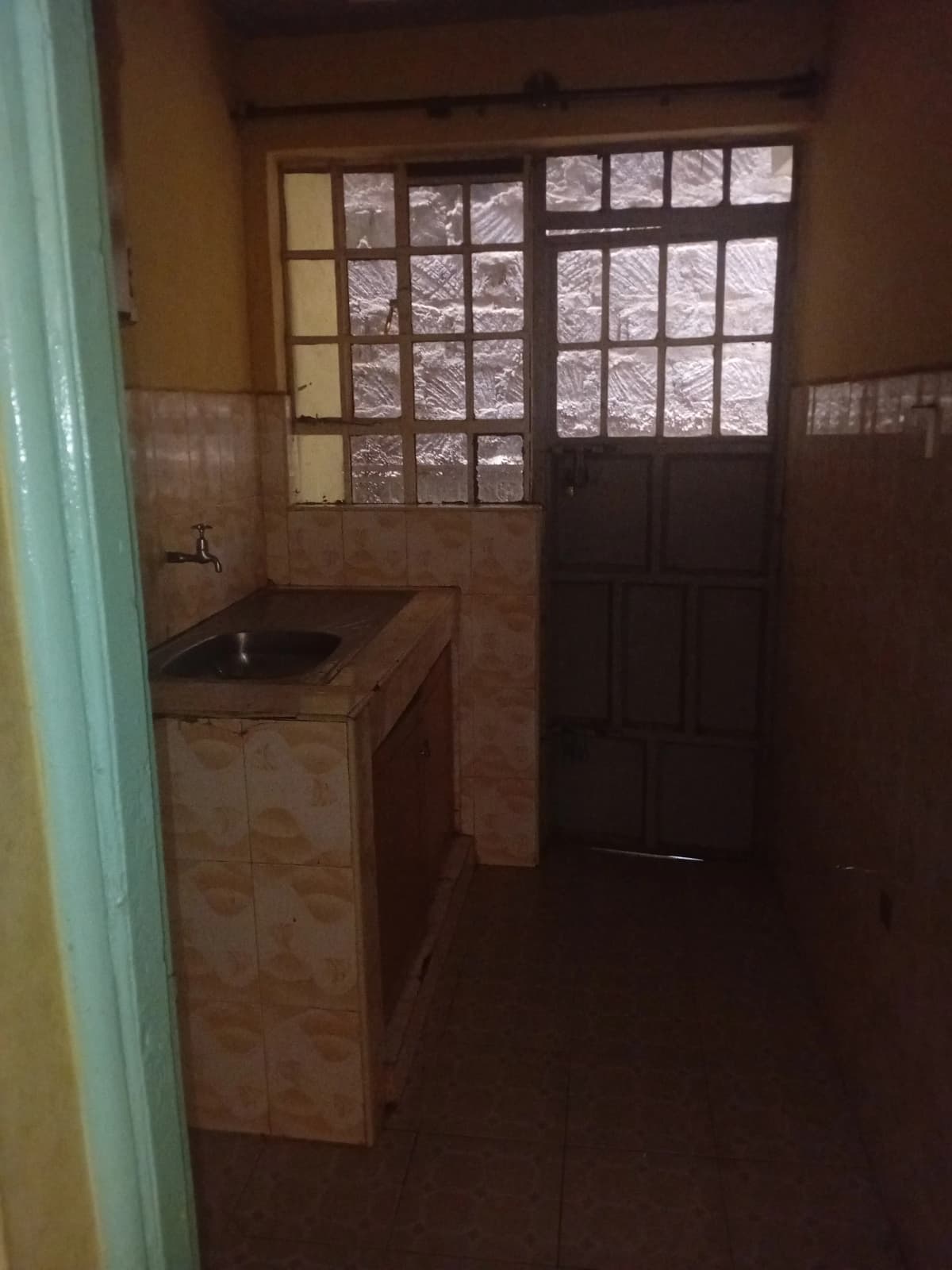 Small kitchen with sink and patterned window overlooking exterior