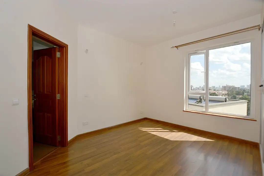 Spacious bedroom with wooden floors and large window view