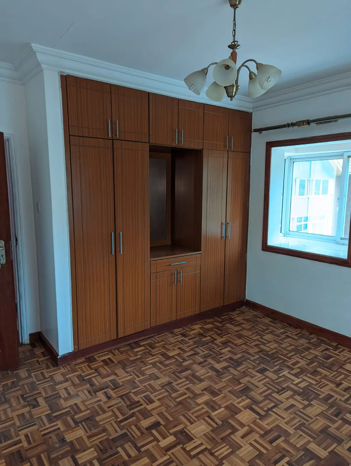 Bedroom with built-in wooden wardrobe and herringbone flooring