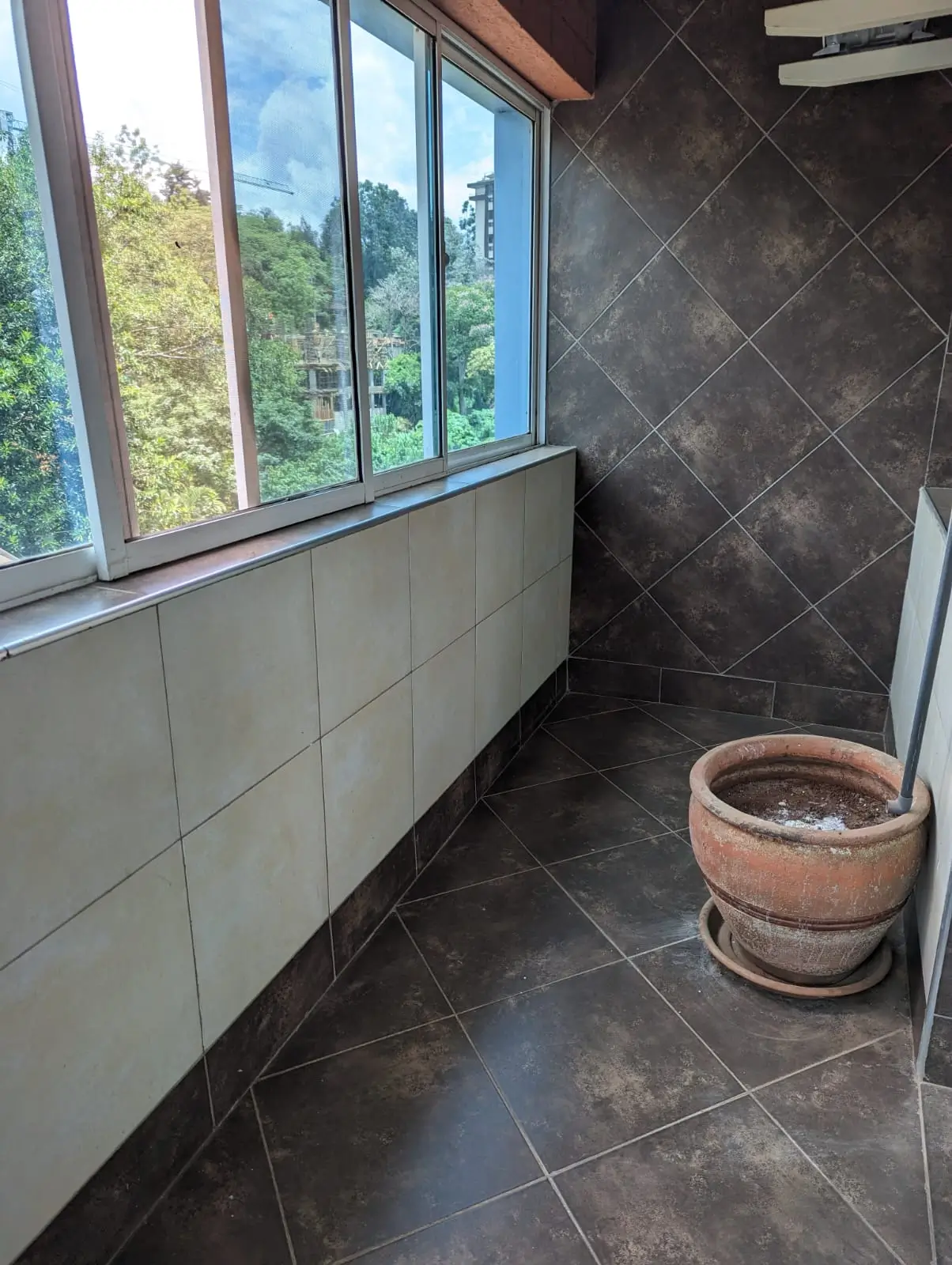 Bathroom with dark tile flooring, white lower wall paneling, large windows