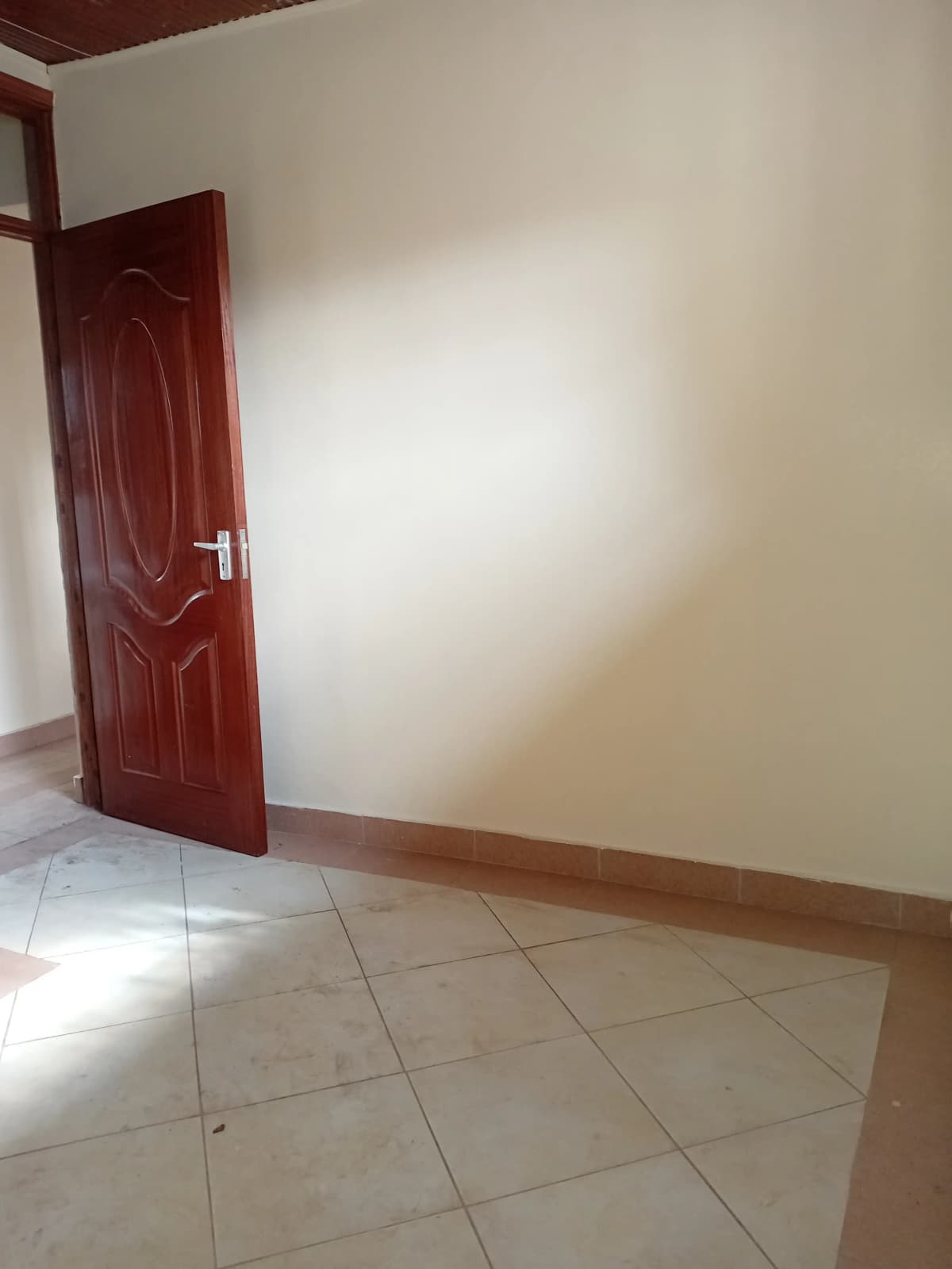 Empty bedroom with tiled floor and burgundy door