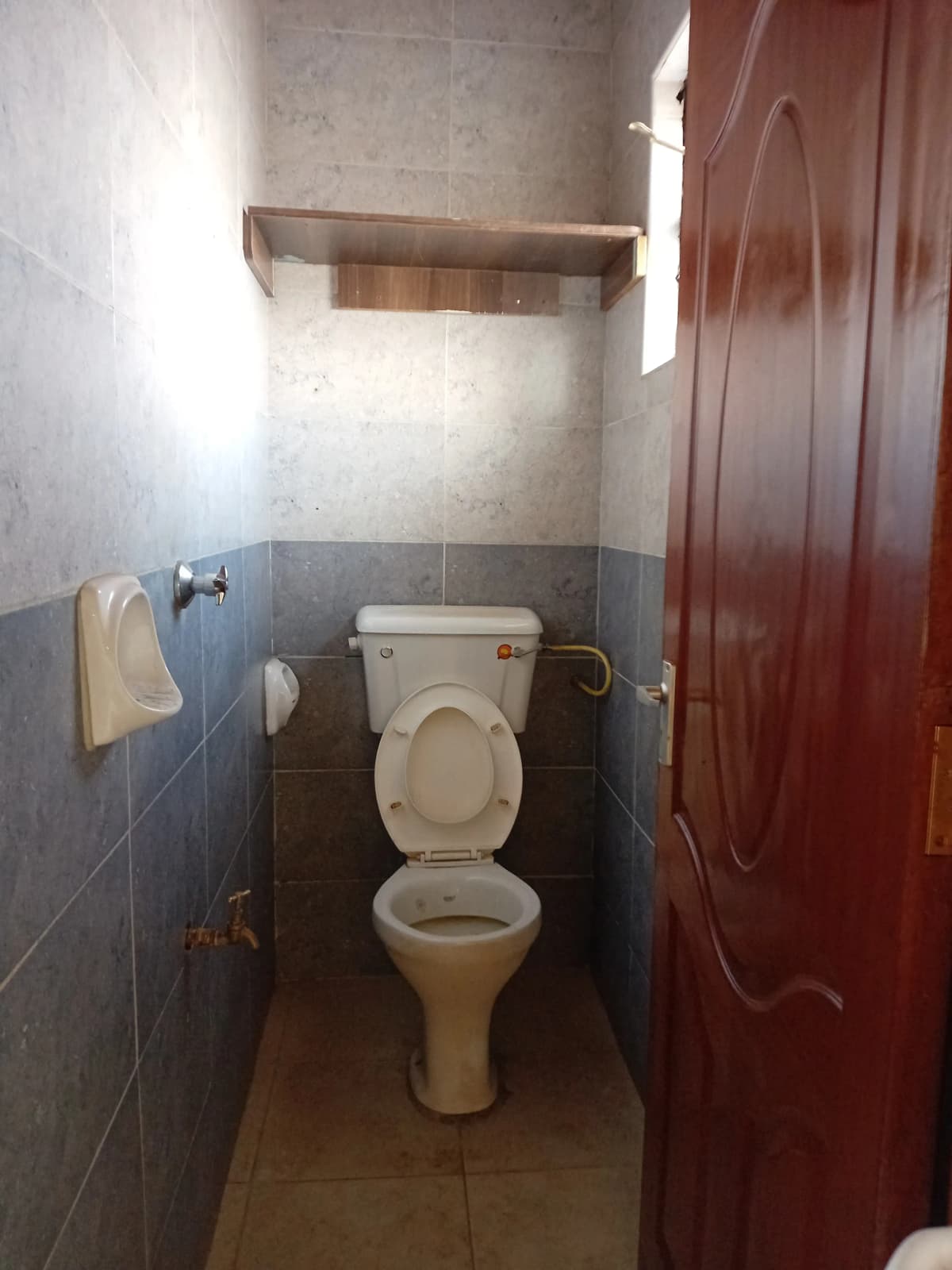 Compact toilet room with basic fixtures and tile walls