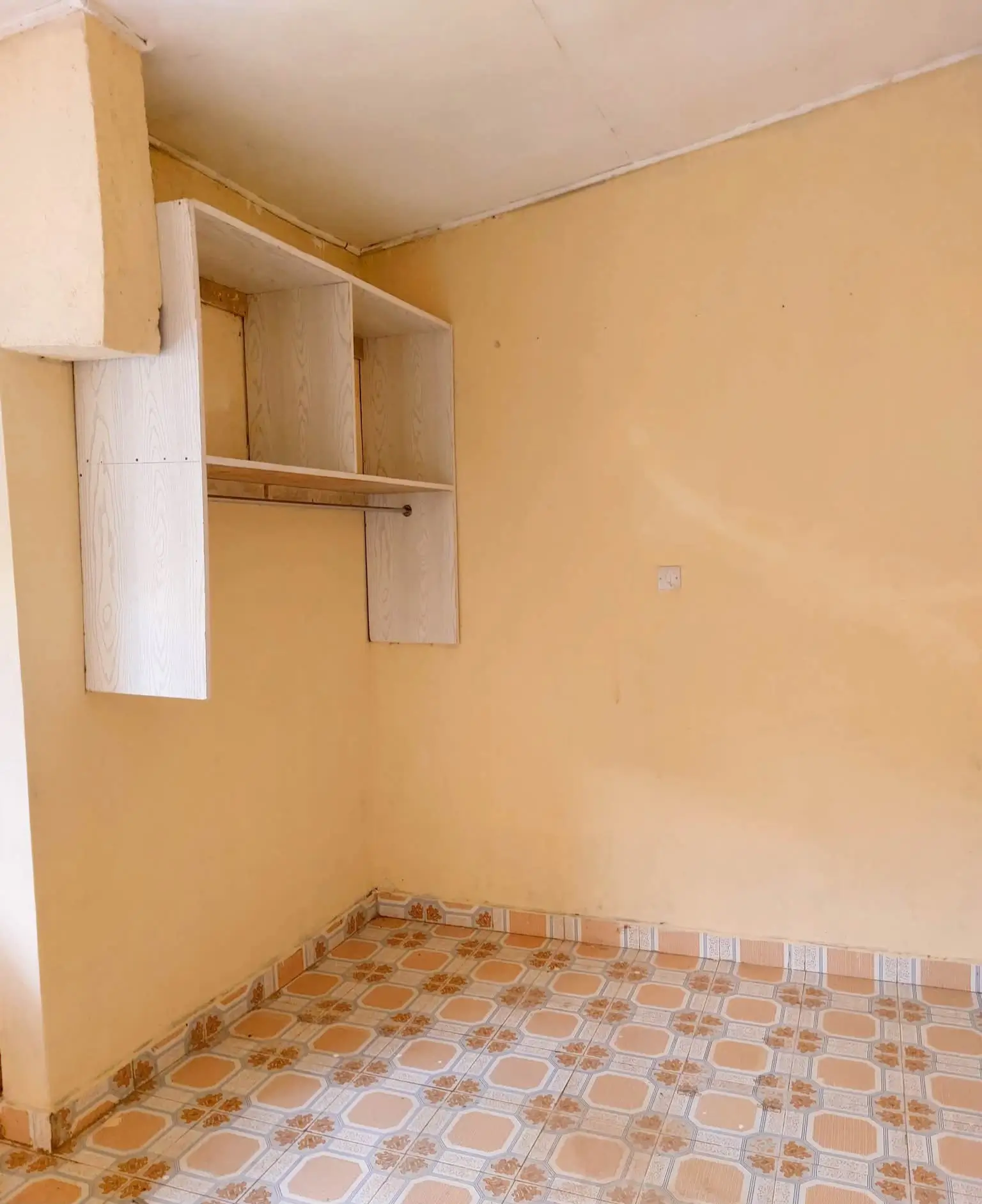 Unfurnished bedroom with built-in shelving and terracotta tile flooring