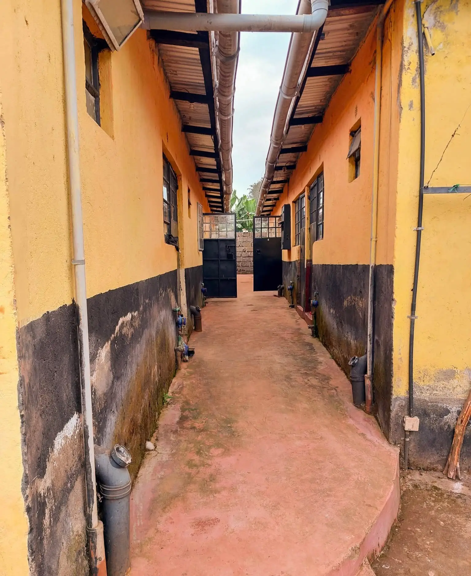 Covered corridor with terracotta flooring and yellow walls