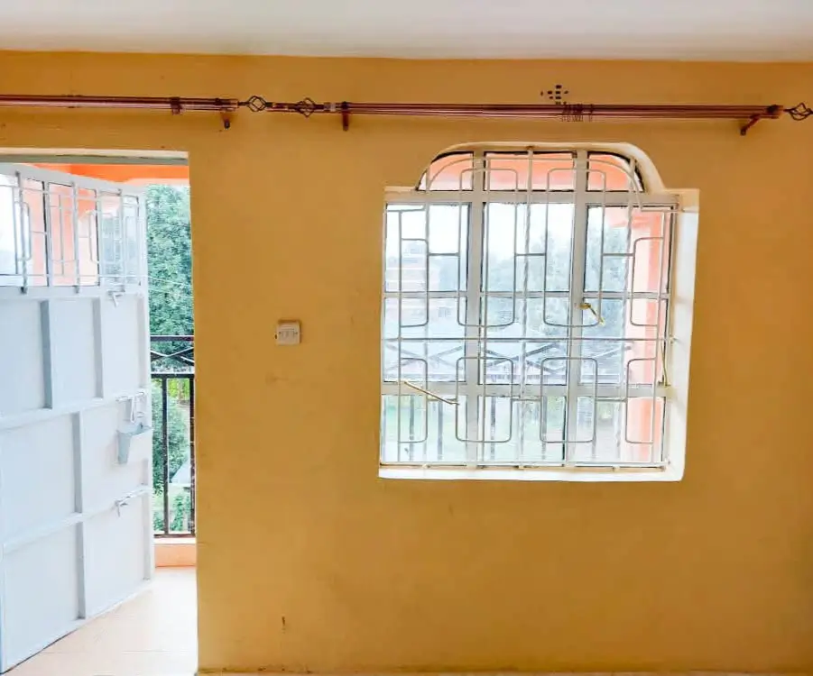 Bright yellow-walled room with barred windows and door access