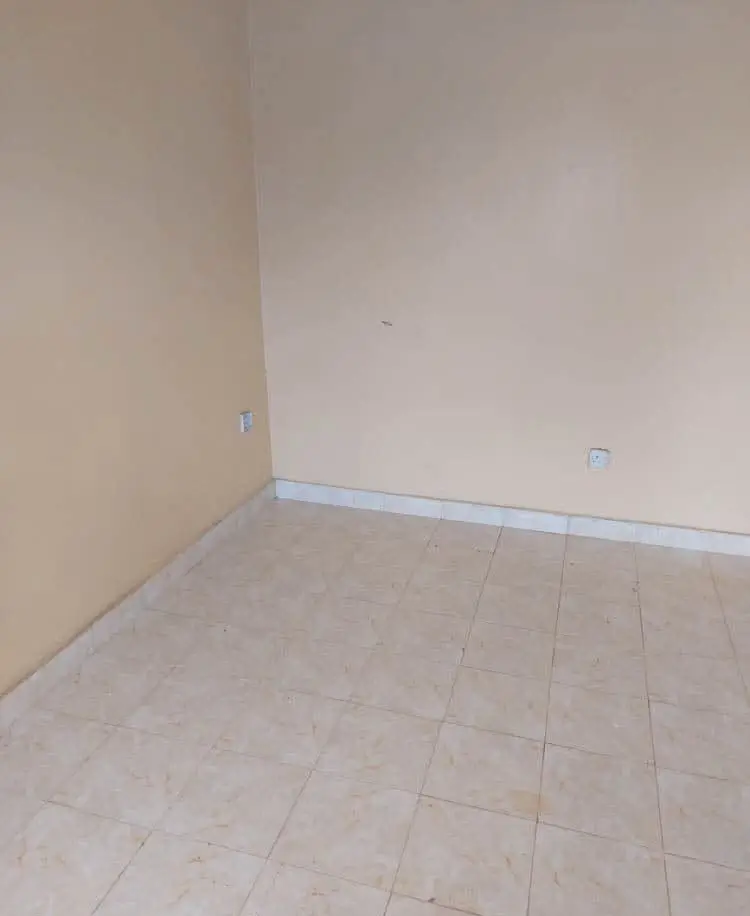 Empty bedroom with light tiled flooring and plain walls