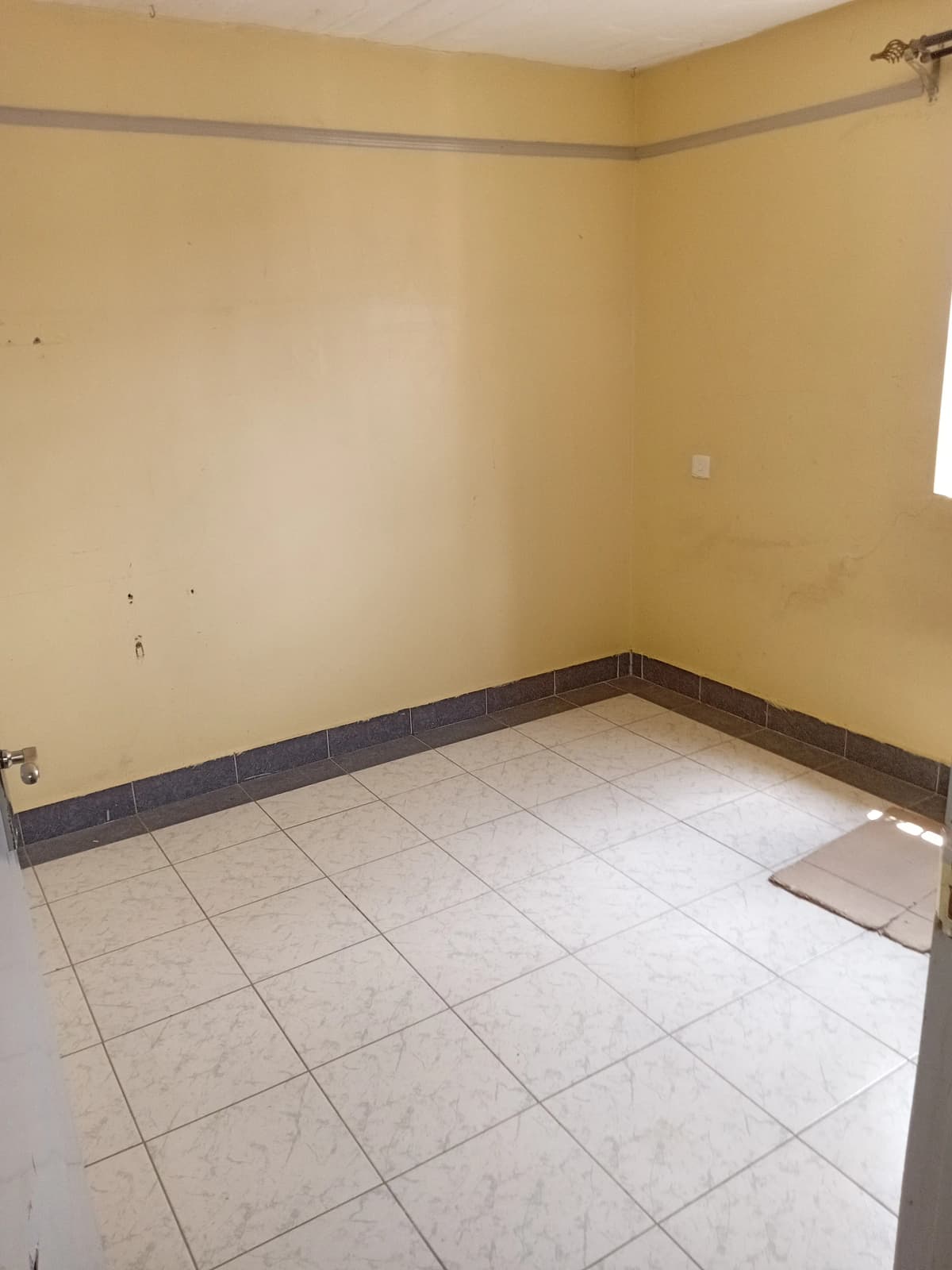 Empty kitchen with tile flooring and dark base trim
