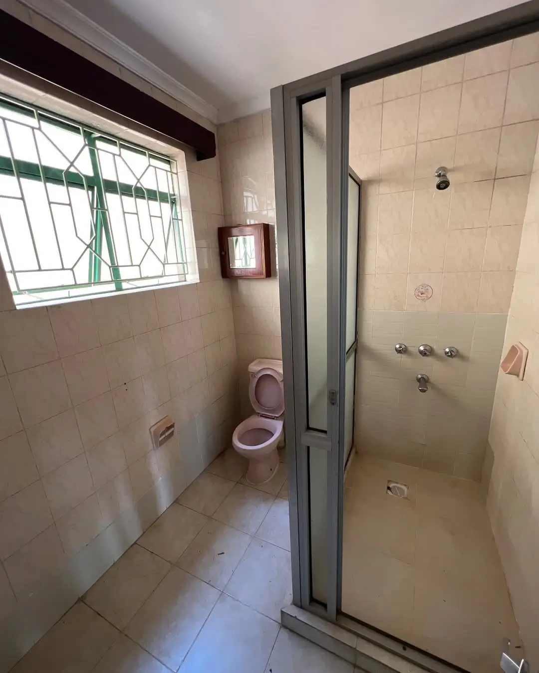 Bathroom with toilet, shower enclosure, and barred window