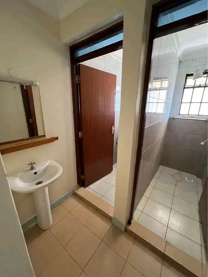 Simple bathroom with pedestal sink and tiled shower area