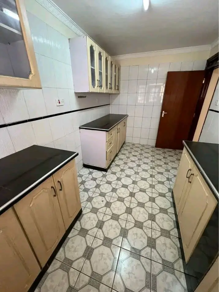 Galley kitchen with black countertops and geometric tile flooring