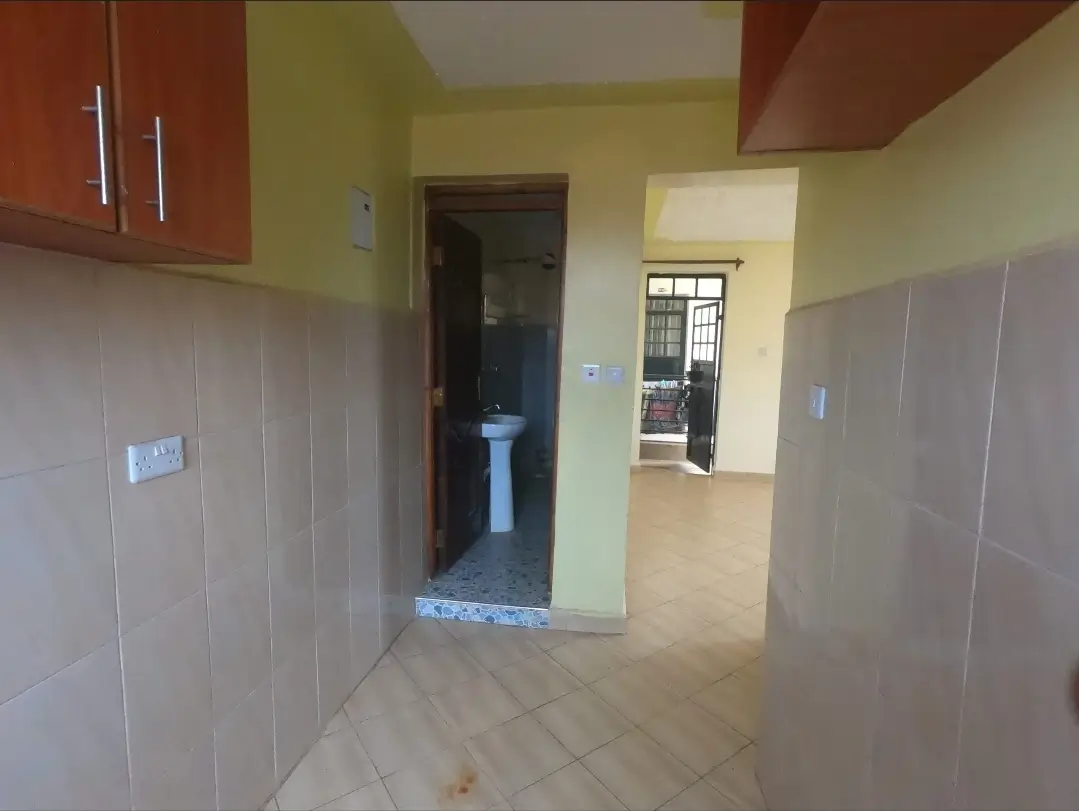 Kitchen with red cabinets, tiled walls, open to corridor