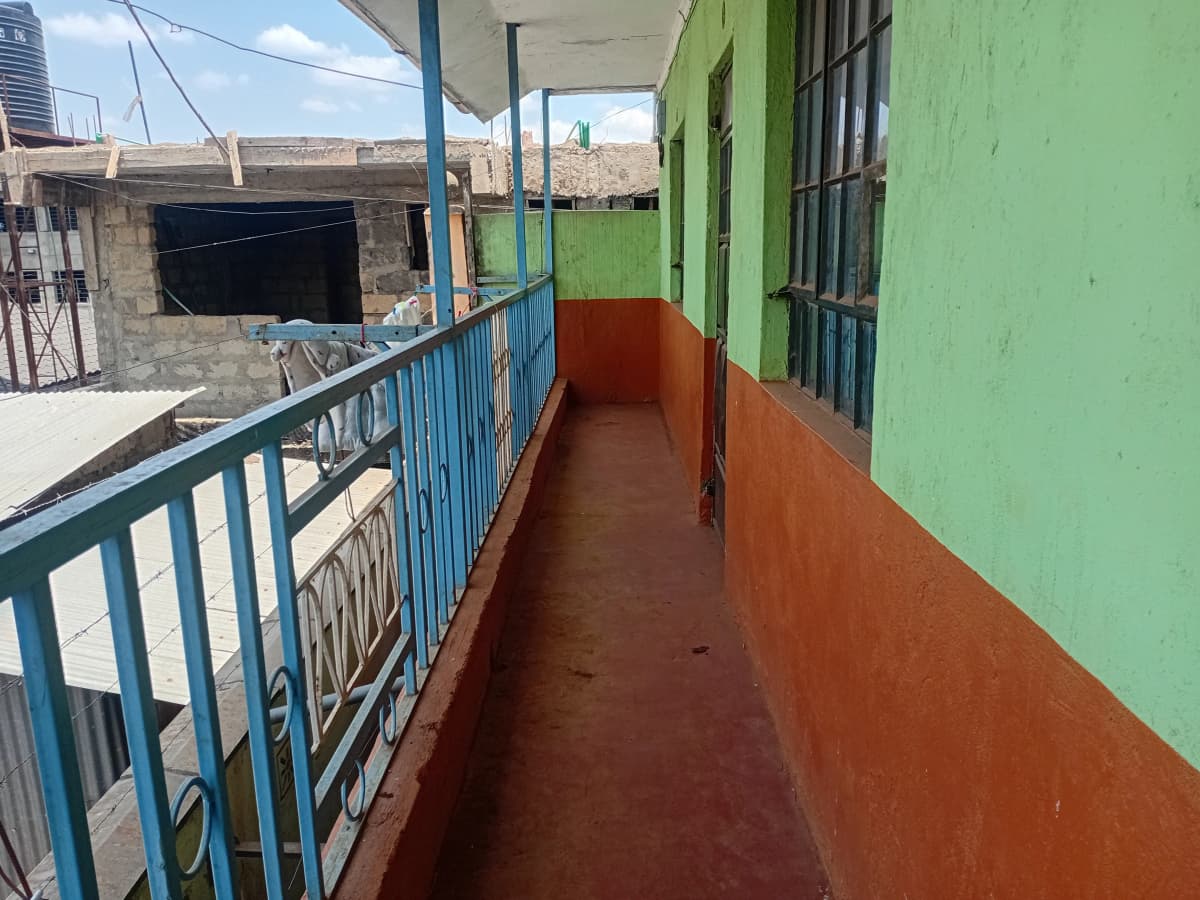 Long covered balcony with blue railing and green wall