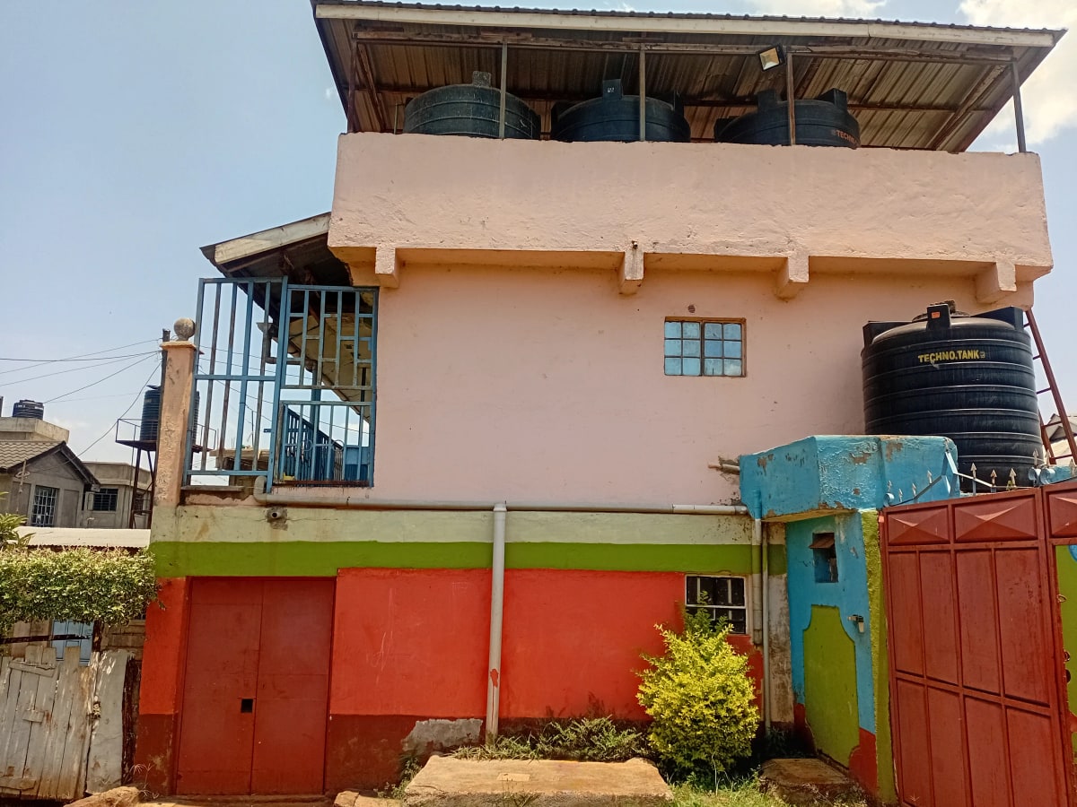 Two-story residential building with pink and red facade, red gates