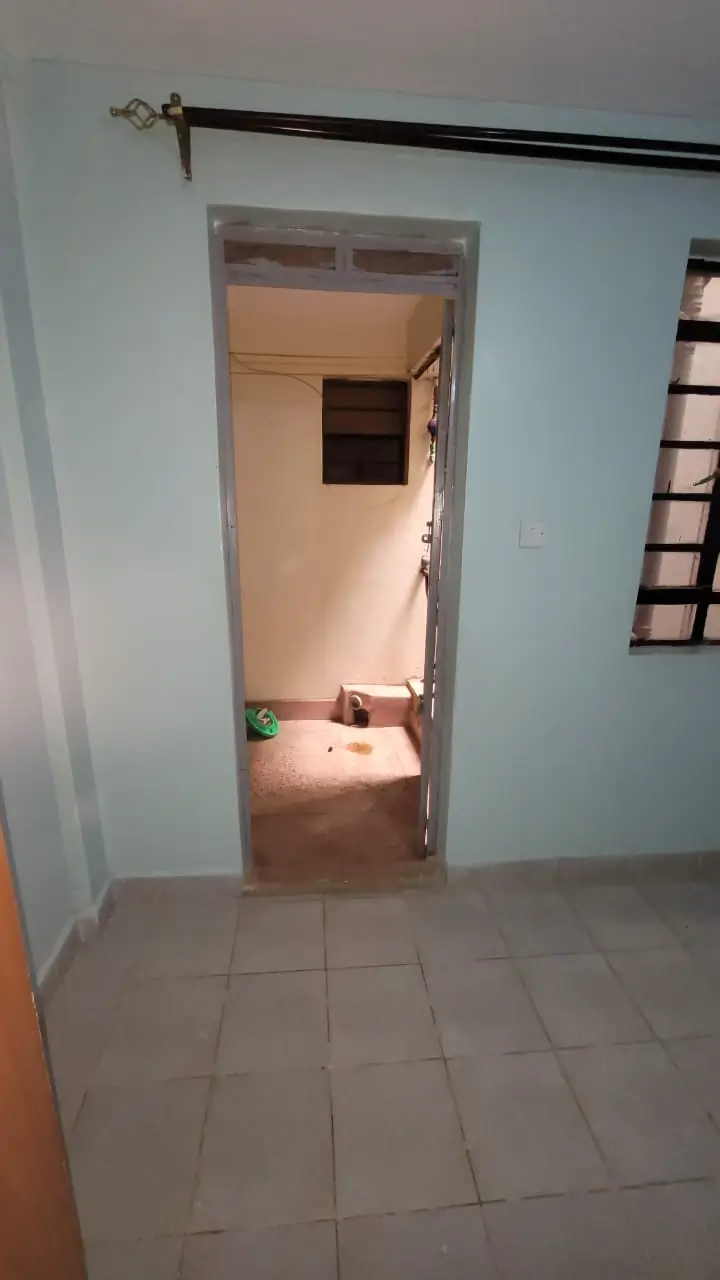 Tiled corridor with open doorway leading to adjacent room