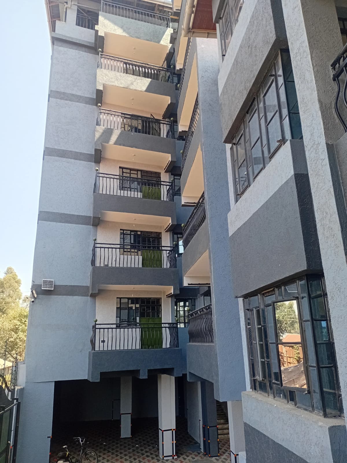 Modern multi-story residential building with balconies and ground parking