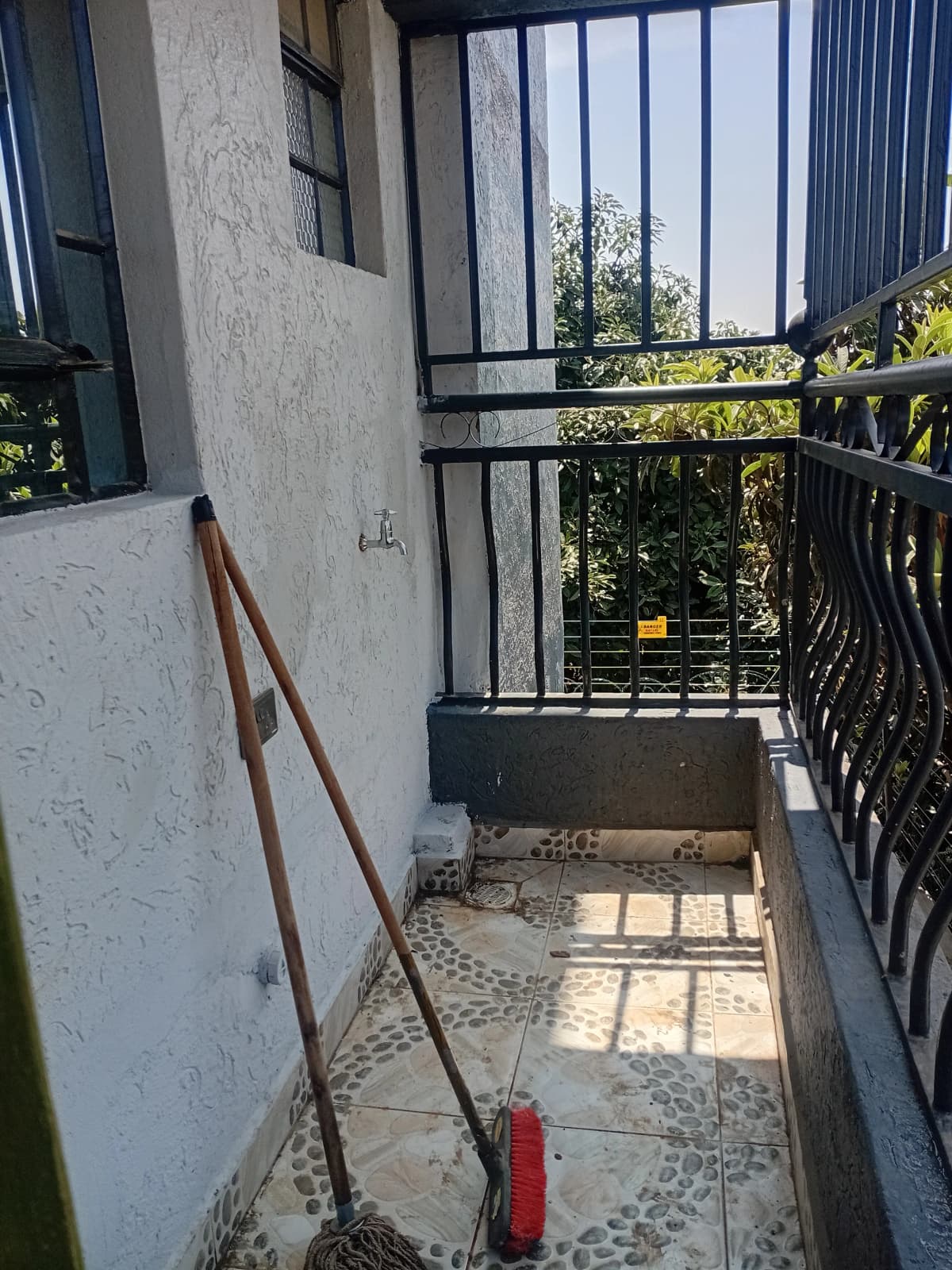 Narrow balcony with metal railings and garden view