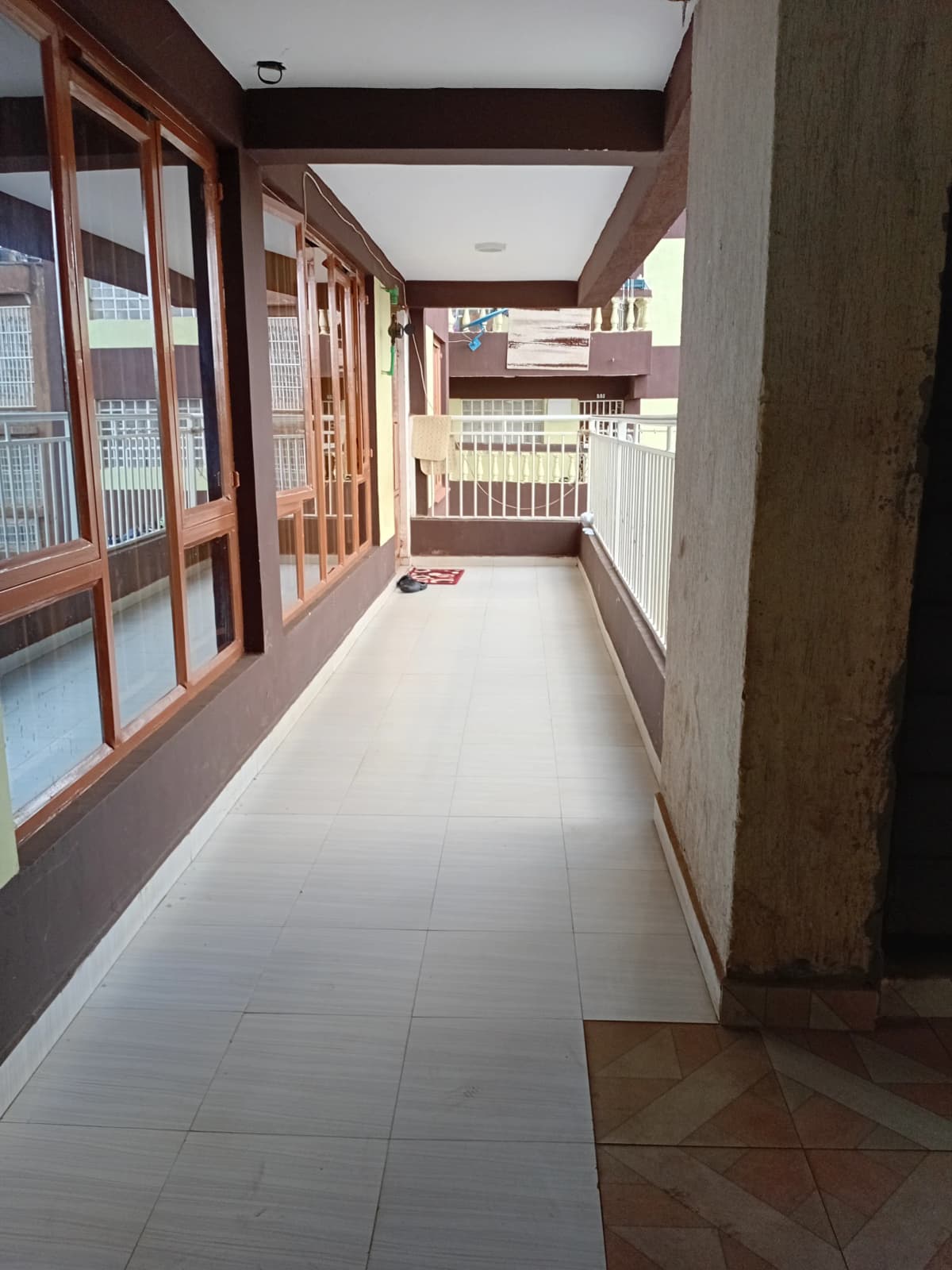 Long covered balcony with wooden frame and white tile flooring