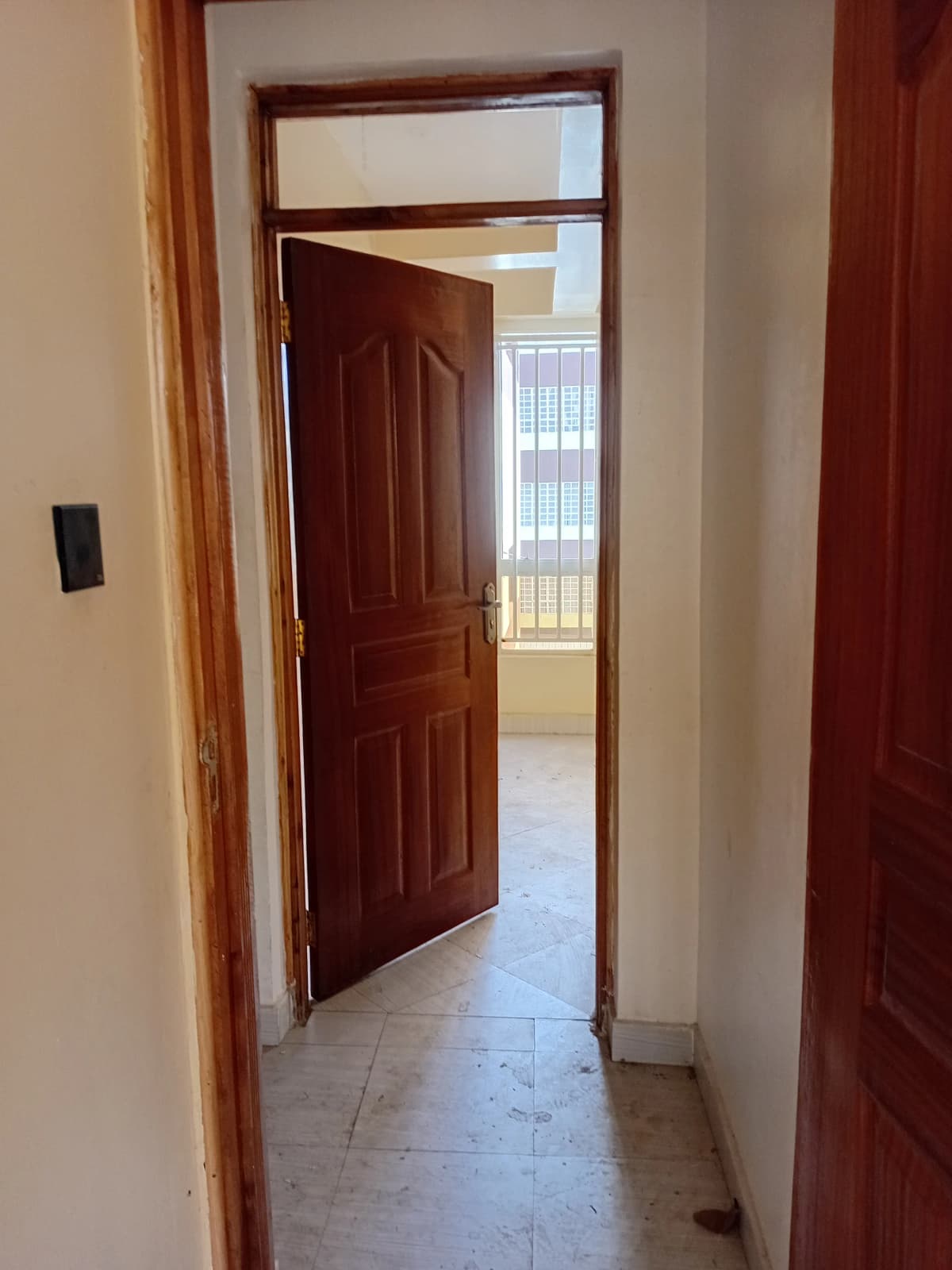 Interior hallway with dark wooden door and tiled flooring
