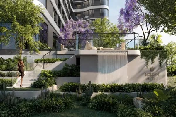 Golden Apple development facade with lush landscaping and water feature