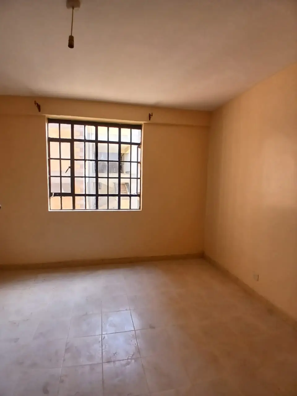 Spacious bedroom with barred window, warm ochre walls