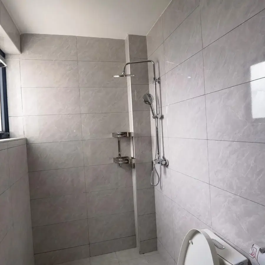 Modern shower enclosure with rainfall showerhead and gray tiles