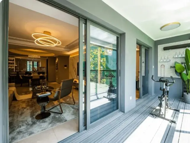 Covered balcony with spin bike overlooking living room via glass doors