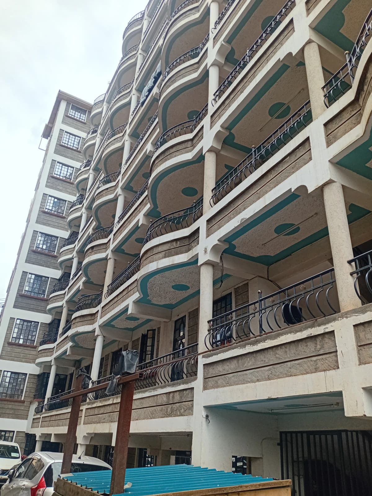 Multi-story residential building facade with balconies and ground-level parking