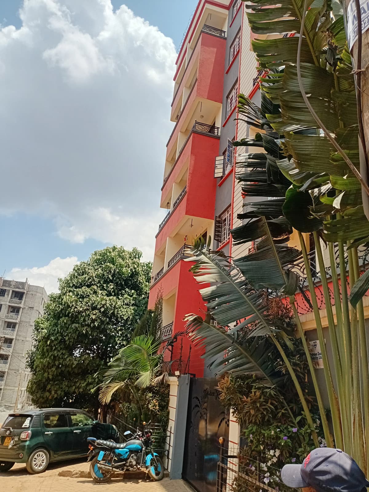 Multi-story residential building facade with red accents and greenery