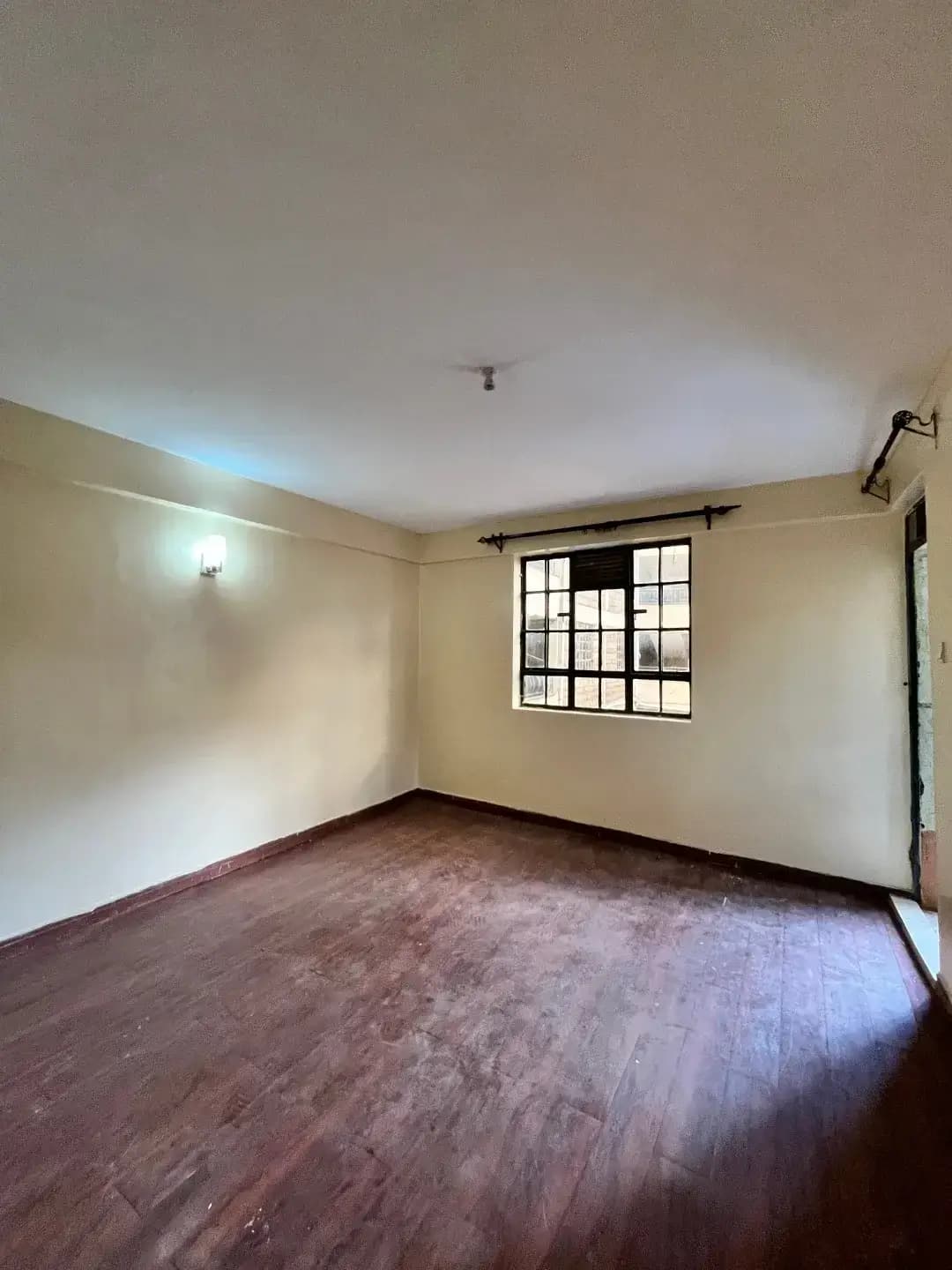 Spacious bedroom with wooden floor and window