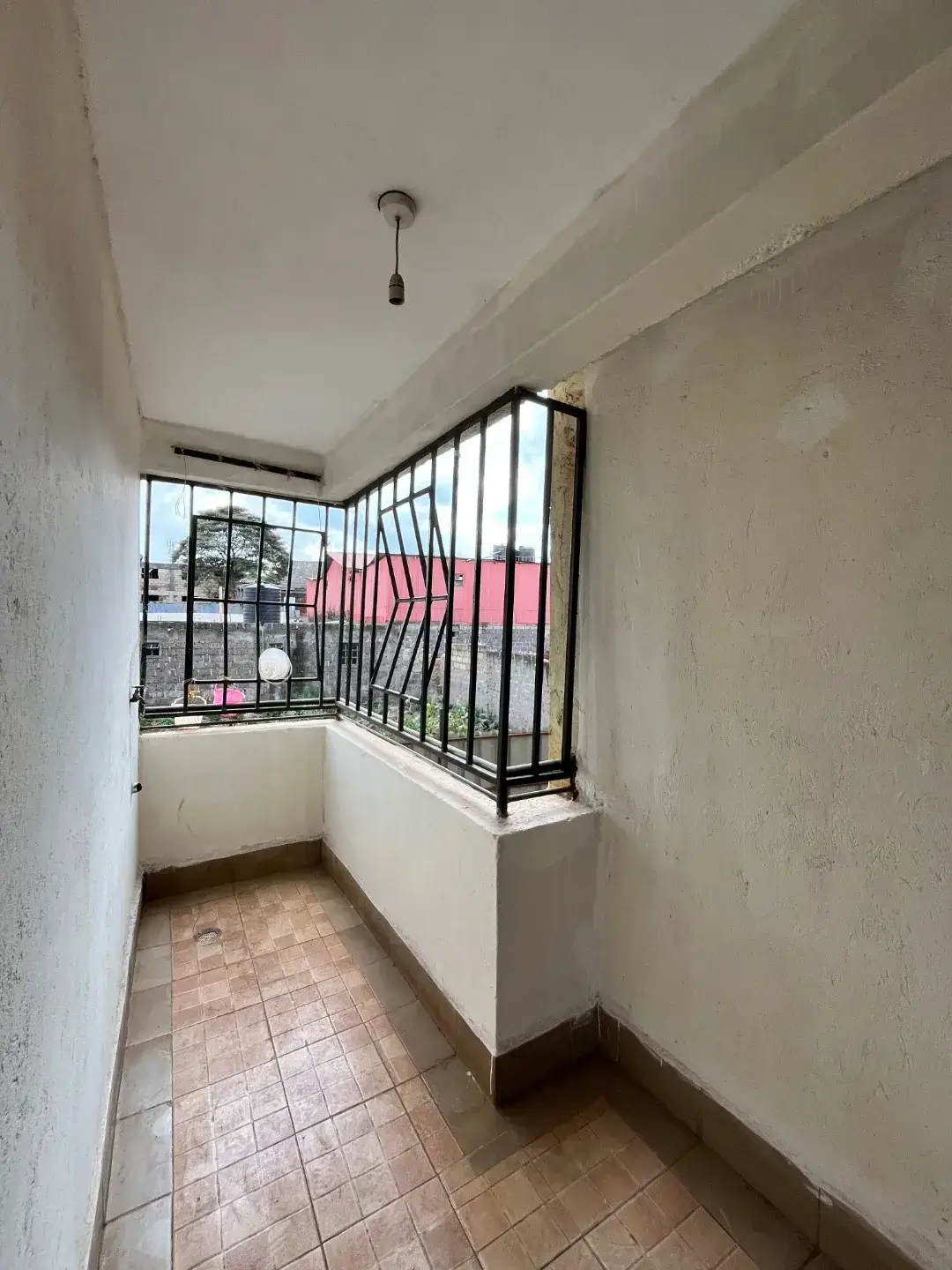 Narrow balcony with black metal railings and terracotta tiles
