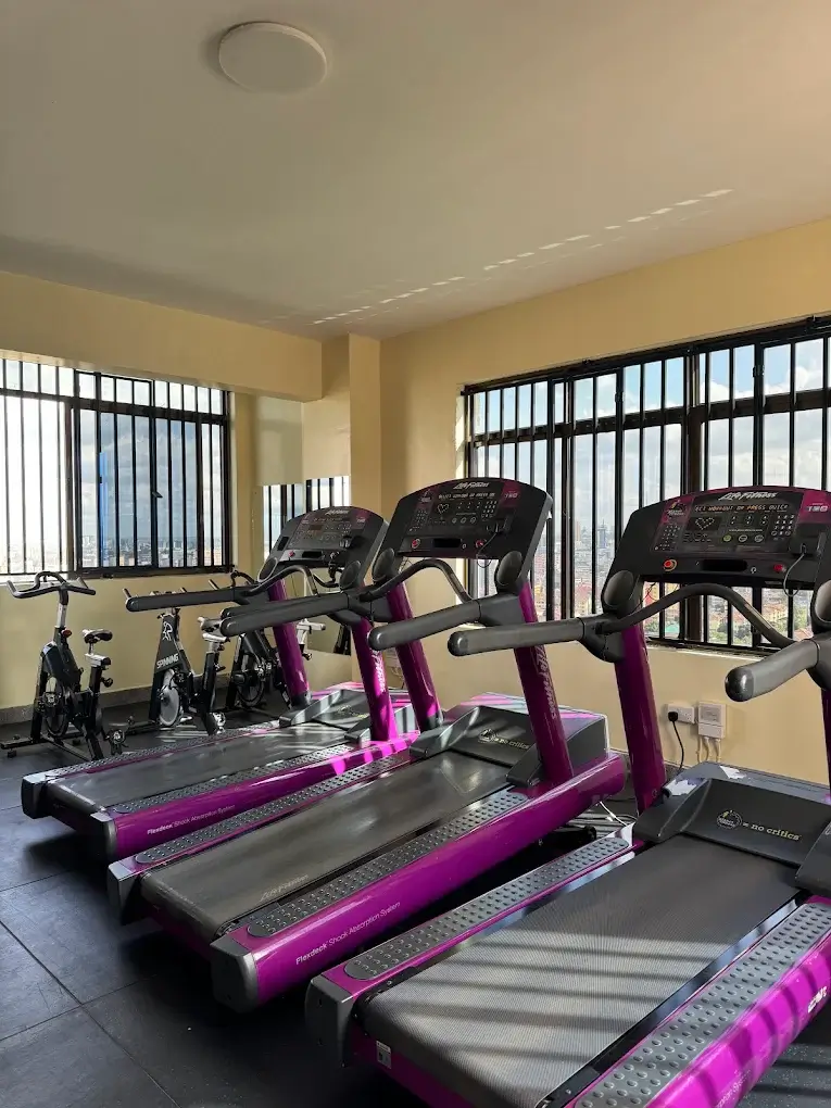 Bright gym with purple treadmills and exercise bikes