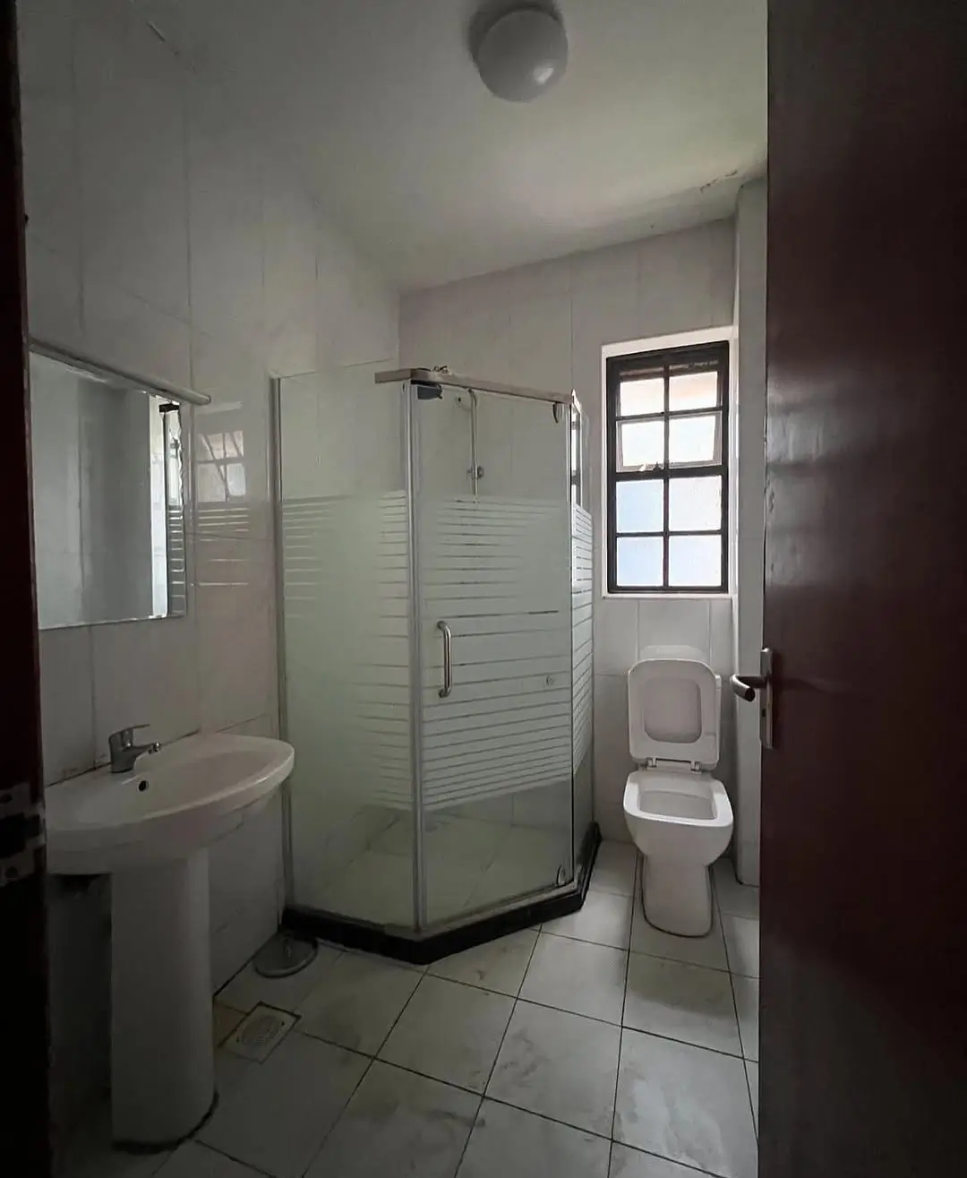 Modern bathroom with corner shower, pedestal sink, toilet