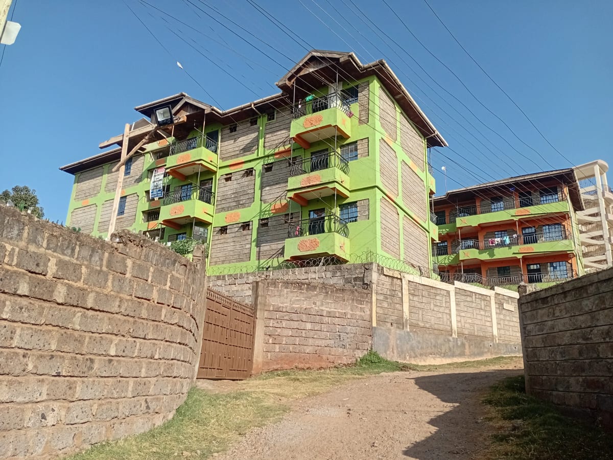 Multi-story residential building with lime-green balconies and perimeter wall