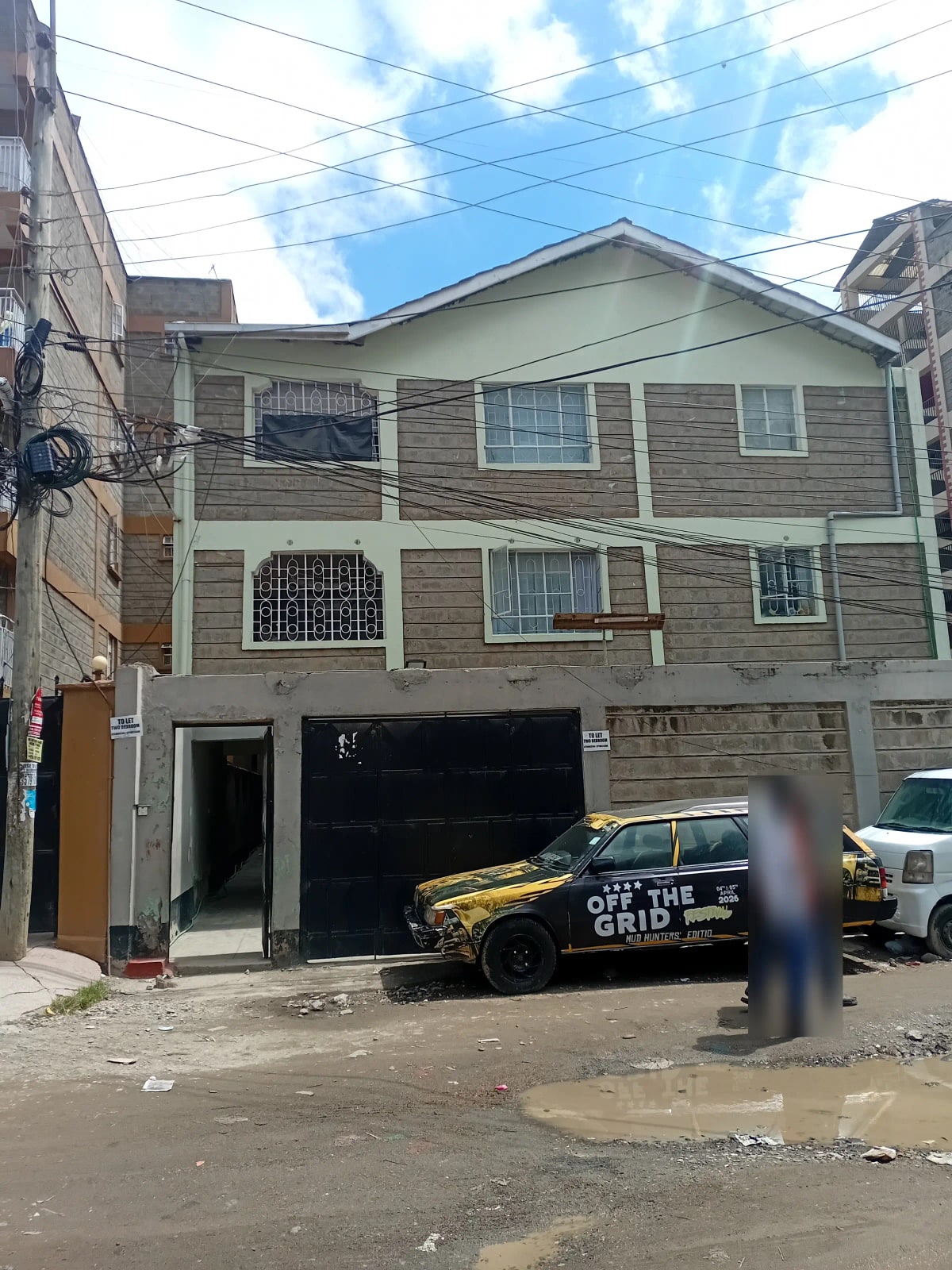 Three-story residential building facade with ground-level parking bay