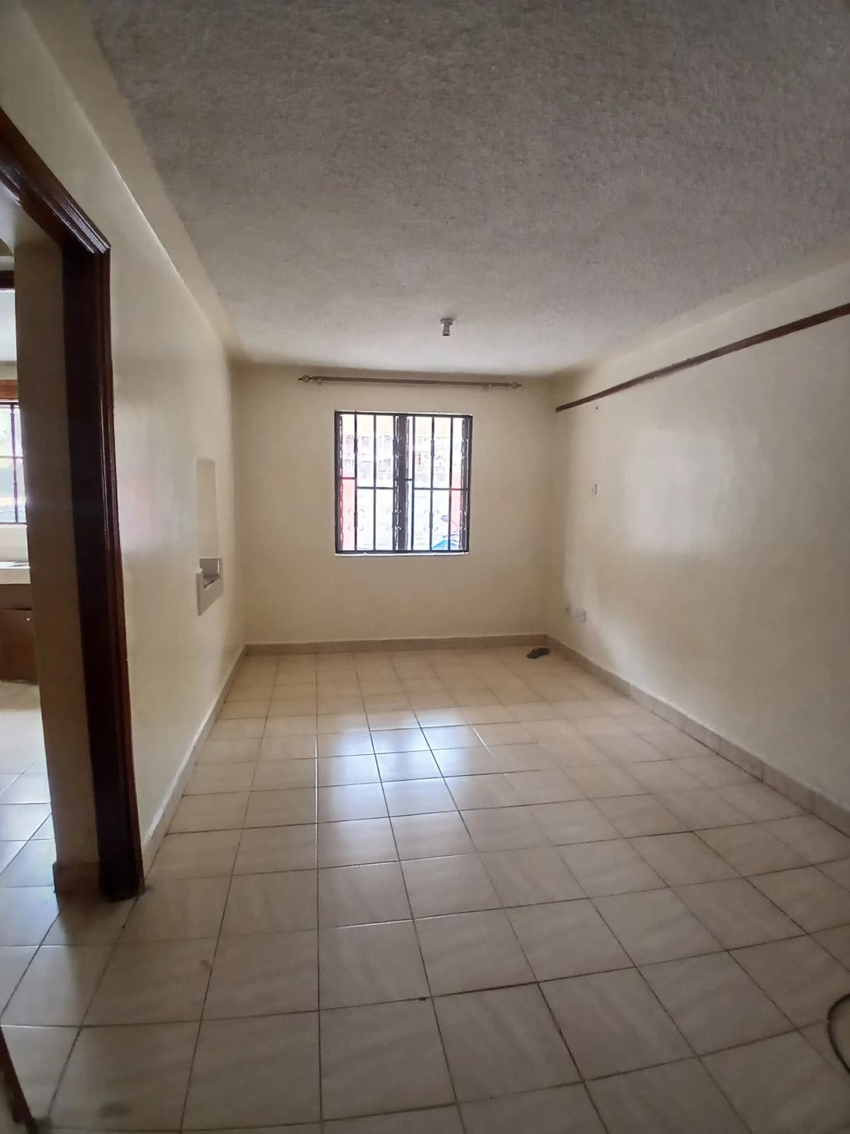 Empty bedroom with tiled floor and barred window