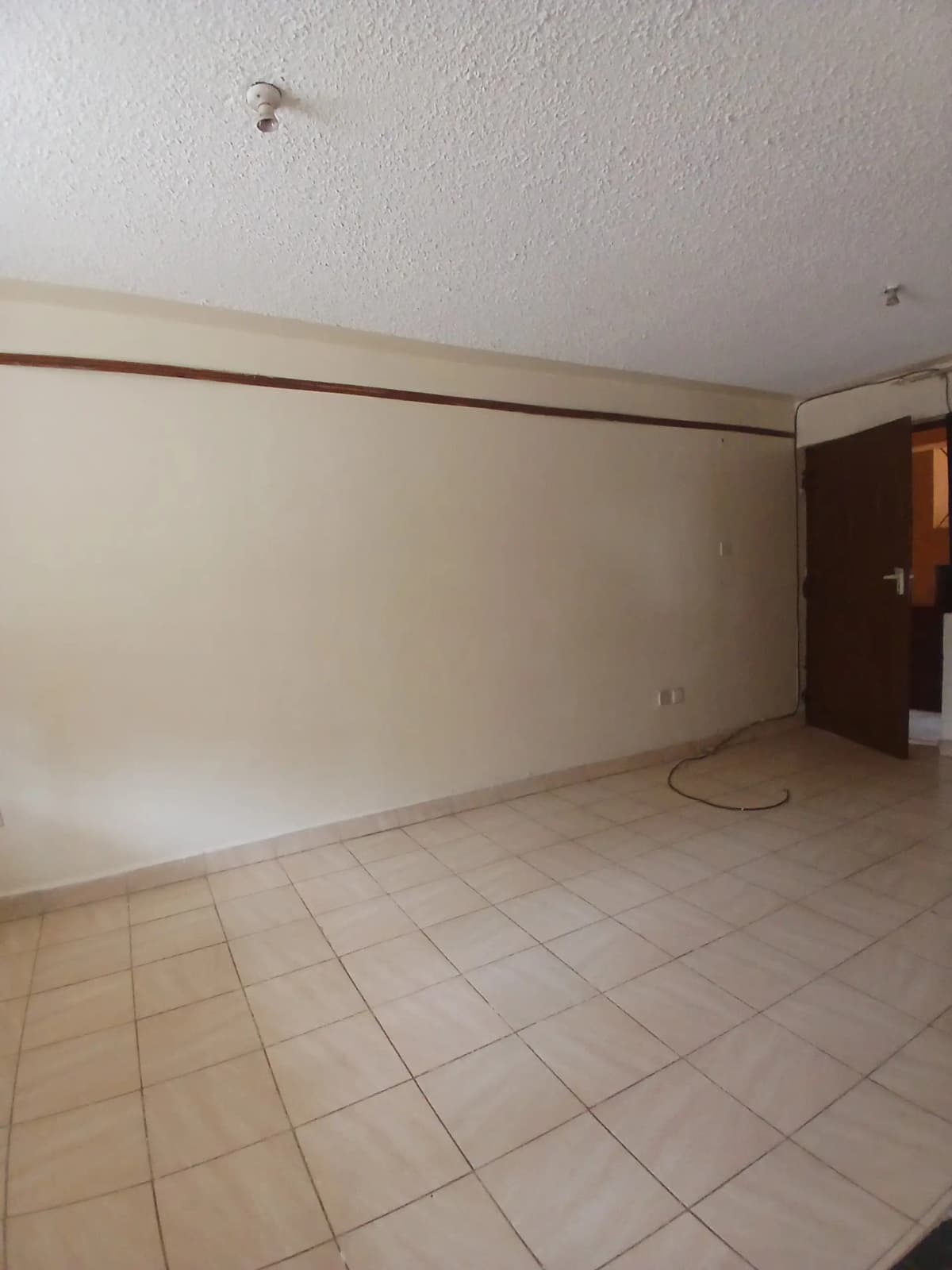 Spacious empty living room with beige tiled flooring