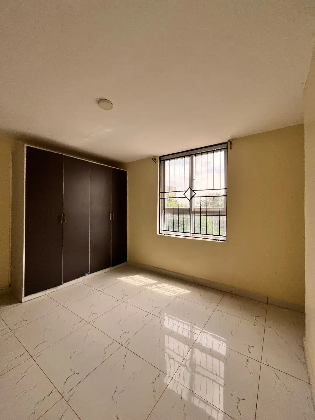 Spacious bedroom with large wardrobe and bright barred window
