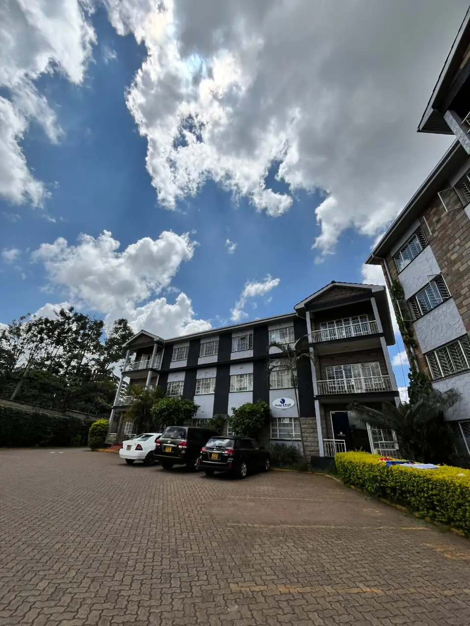 Modern apartment building with paved driveway and parked vehicles