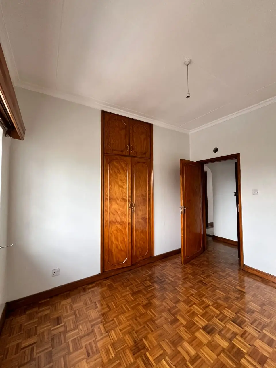 Spacious bedroom with wooden wardrobe and herringbone flooring